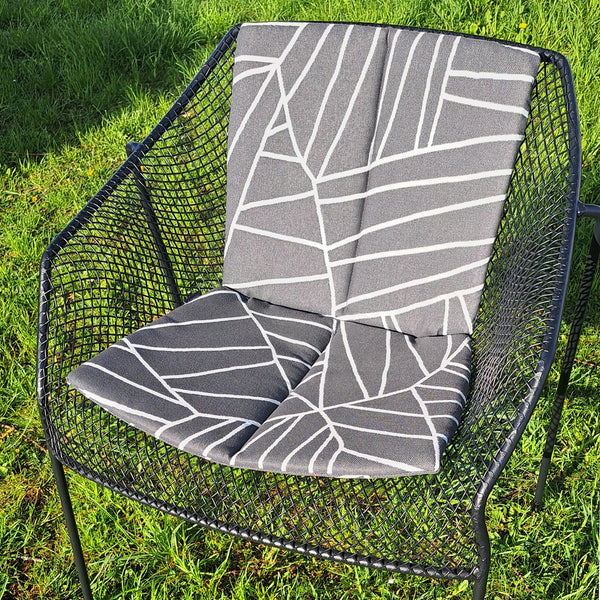  Vollpolster Outdoor-Sitzkissen für Heaven Armlehnstuhl von EMU in schwarz mit asymmetrischen weißen Linien auf einem Stuhl im Garten.