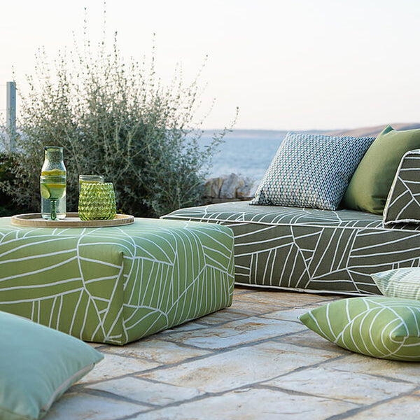  Moderne Outdoor-Sitzgruppe  am Meer mit Sitzhocker als Tisch in grünen Farbtönen.