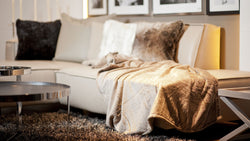 Fine Decke Soft Velvet Taupe auf einer Couch dekoriert.