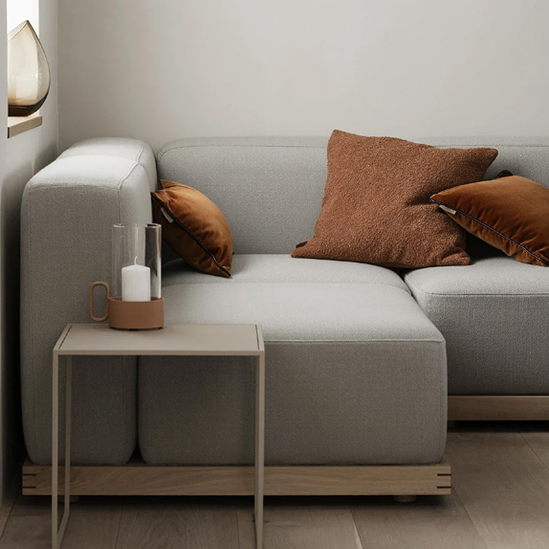 Blomus Couch in grau auf der drei Kissen aus Samt und Bouclestoff liegen in der Farbe tan.