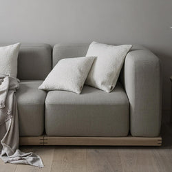 Drei weiße Blomus Boucle Kissenhüllen auf einer grauen Couch.