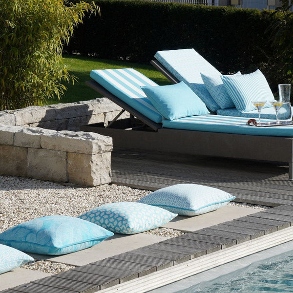  Outdoorkissen und Outdoorbankauflagen in versschiedenen Blautönen auf modernen Sonnenliegen am Pool.